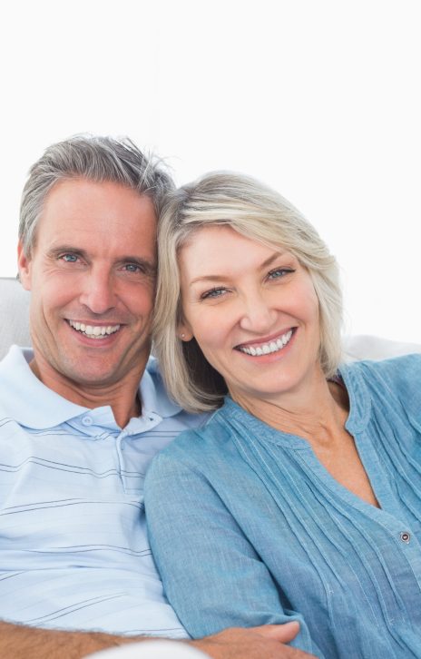 Happy couple relaxing on their couch smiling at camera